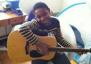 My son, Noah Collins, hanging out in his room with his guitar (Image Source: Angelia Levy, May 2014)